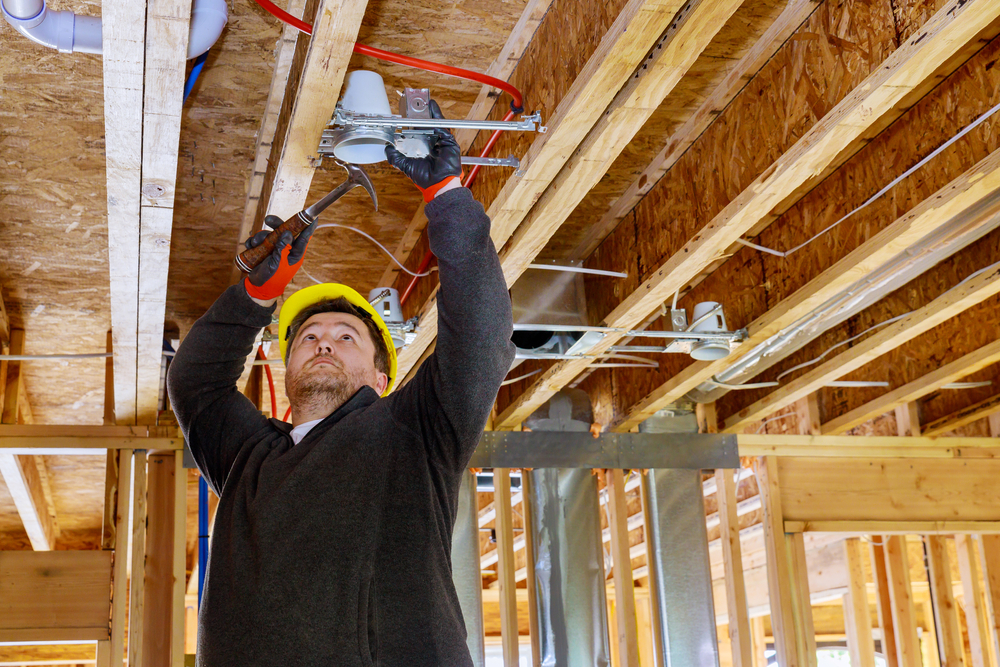 The,electrician,nailing,to,the,ceiling,lamp,,installs,the,lighting