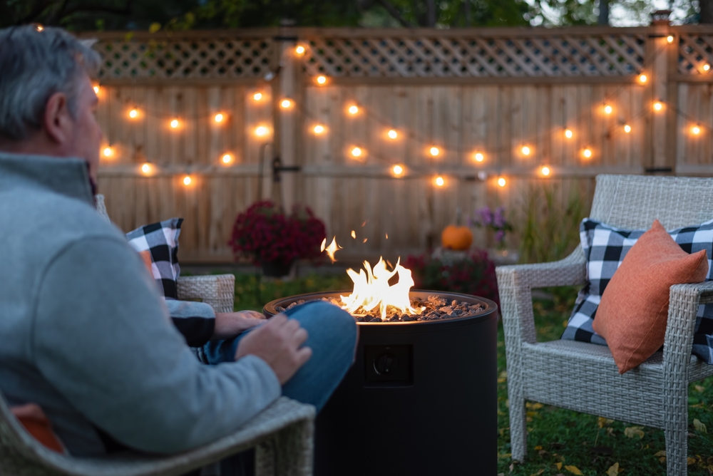 Backview,of,a,man,sitting,by,a,backyard,fire